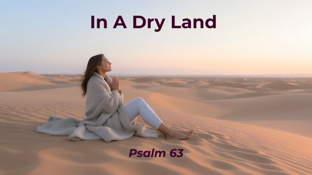 Woman sitting on a sand dune with hands folded in prayer with the text "In A Dry Land - Psalm 63"